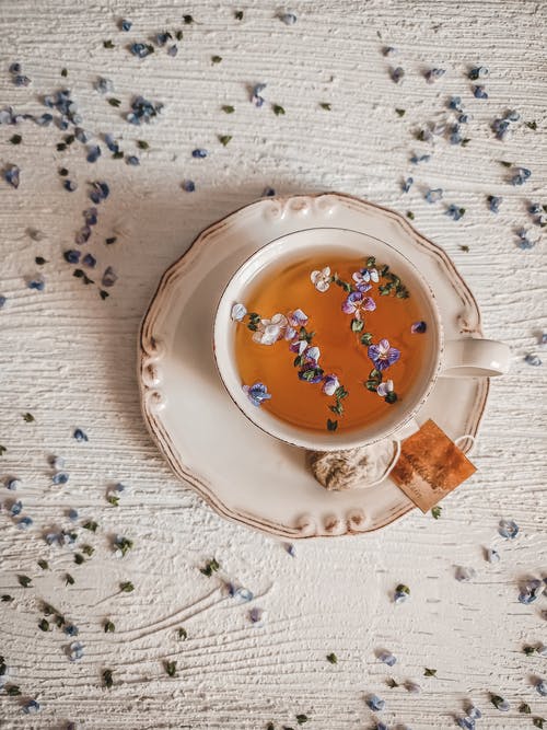 tea in ceramic cup sprinkled with flower petals