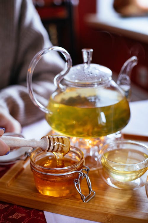 tea in glass pot on tray with honey